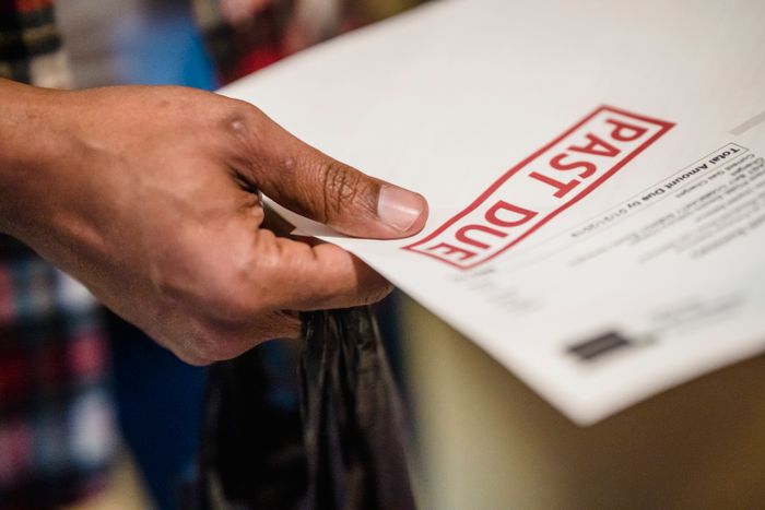 A hand holding an envelope stamped past due